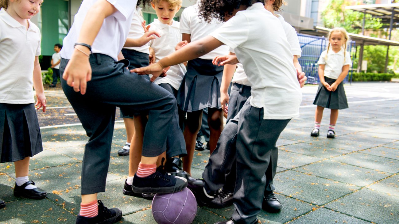 Group of diverse kindergarten students playing soccer together