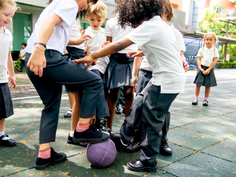 Group of diverse kindergarten students playing soccer together
