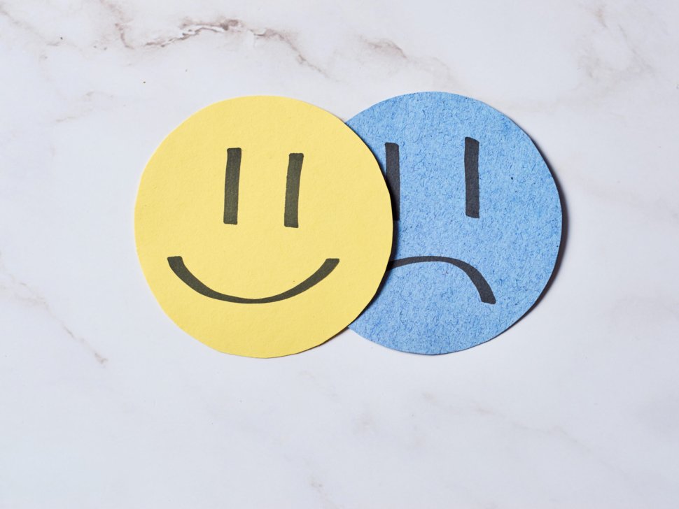 Sad face covered by happy face. Depression and sadness disorder concept.