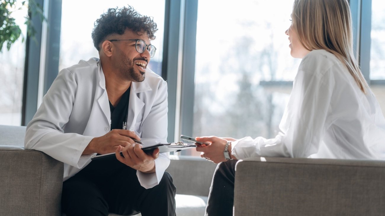 Sitting and talking. Man and woman are indoors in modern building.