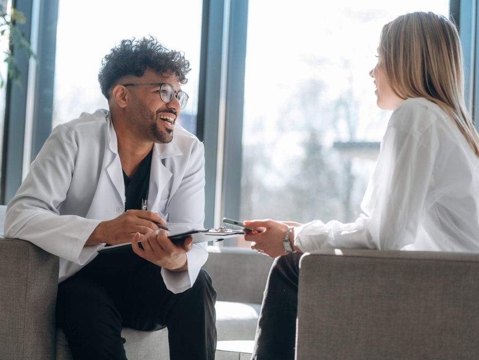 Sitting and talking. Man and woman are indoors in modern building.